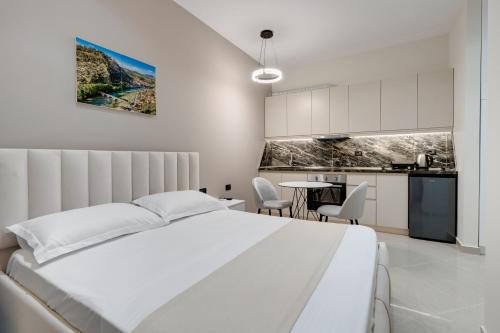 a white bedroom with a bed and a table at Swimming Pool - Marko Studios Berat in Berat