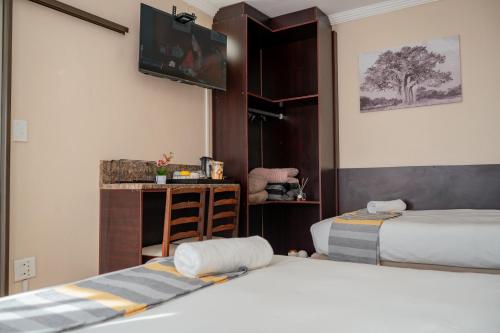 a bedroom with two beds and a tv on the wall at Infinity Home BnB in Leribe
