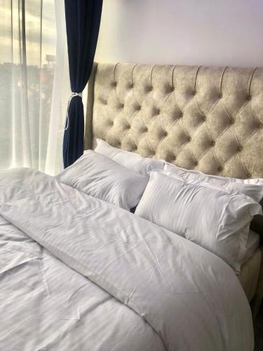 a bed with white sheets and pillows in front of a window at Tsavo Stanley, Kiambu La Mayan in Kiambu