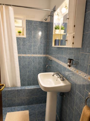 a blue tiled bathroom with a sink and a shower at Algarrobos del Mirador in Santa Rosa de Calamuchita