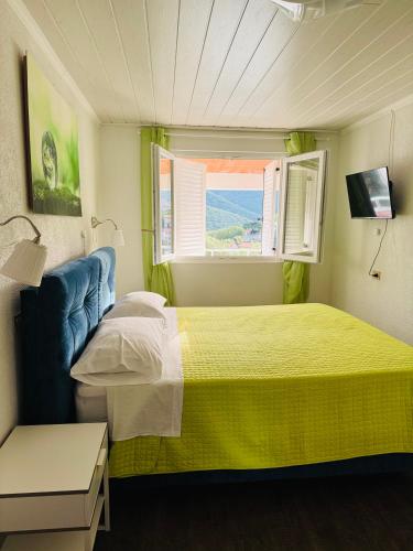a small bedroom with a yellow bed and a window at Casa Mare in Rabac