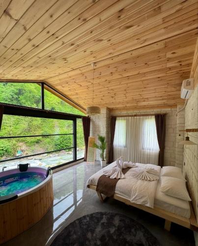 a bedroom with a large bed and a tub at Villa Del Rio Karadeniz River Palace Ayder in Çamlıhemşin