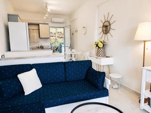 a living room with a blue couch and a kitchen at Siviri Sea & Forest-Cozy Apartment with Garden & Nature Views in Siviri