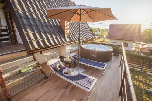 a balcony with a hot tub and a chair and an umbrella at Riverside Home Laura in Karlovac
