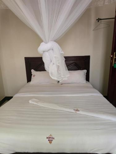 a bedroom with a bed with a white comforter at Morika Hotel in Mbarara