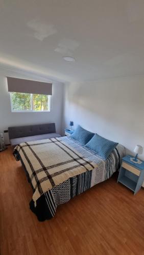a bedroom with a bed with a blanket and a window at Cabaña en pleno centro in Valdivia