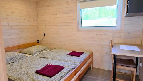 two beds in a room with a desk and a window at Ranczo Wyszowate Domki in Wyszowate
