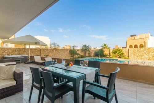 a patio with a table and chairs and a pool at Wellness Hygge Modern Gozitan Apartment - Happy Rentals in Taʼ Sardina