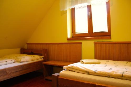 two beds in a room with yellow walls and a window at Chata pod Lazíkom in Liptovský Hrádok