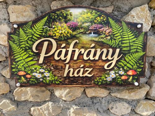 a sign on a stone wall with a garden sign at Páfrányház in Fertőd