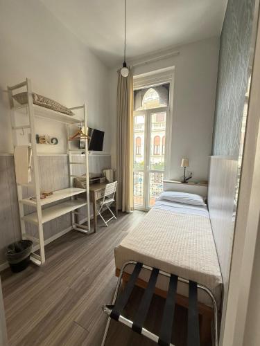 a bedroom with a bed and a desk and a window at Hotel Malta in Milan