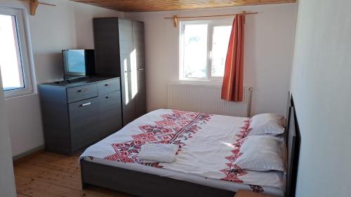 a bedroom with a bed and a dresser with a television at Casa Cătălin-Puntea Craiului in Şirnea