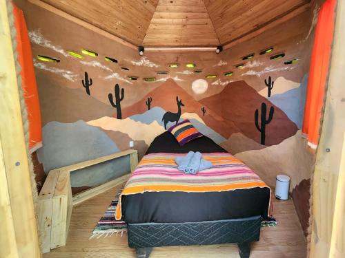 a room with a bedroom with a mural of a forest at Casa Voyage Hostel in San Pedro de Atacama