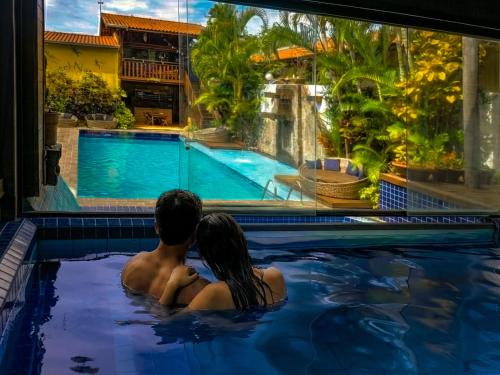 a man and a woman sitting in a swimming pool at Hotel Natural Brotas - SPA & Lazer in Brotas