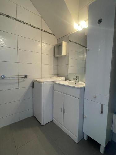 a white bathroom with a sink and a mirror at Studio de plein pied avec terrasse in Joncherey