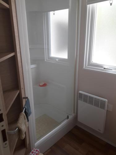 a bathroom with a glass shower door and a window at danseuse 33 in Parentis-en-Born