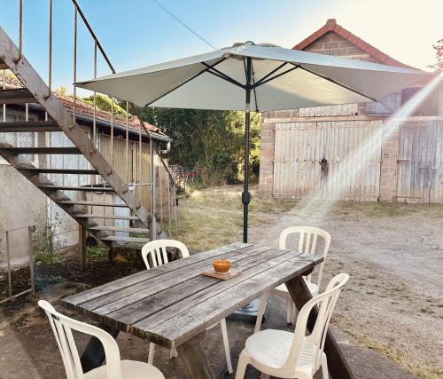 a wooden table with white chairs and an umbrella at S17 Parking Wifi 2 chambres, 4 personnes Réduc à la semaine ou mois in Imphy