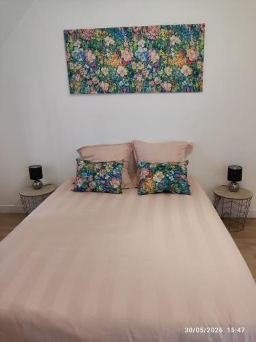 a bed with two pillows and a painting on the wall at Gîte pres de Giverny in Gasny