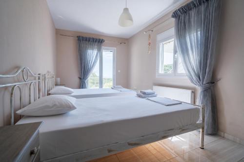 two beds in a room with two windows at La Sirenetta Residence in Syvota