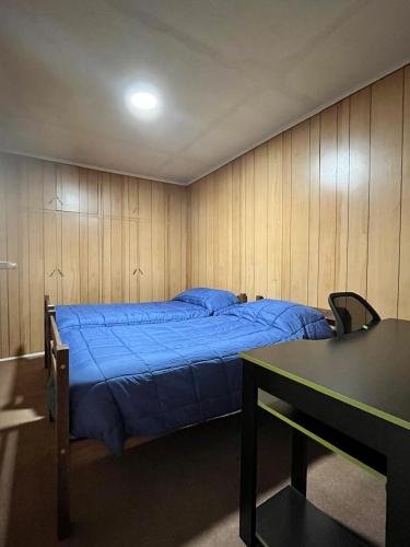 a bedroom with a blue bed and a table at La Casona - Refugio Austral in Punta Arenas