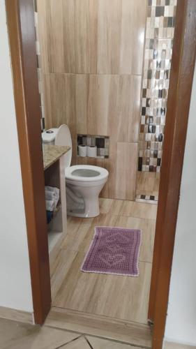 a bathroom with a toilet and a purple rug at Recanto Vieira in Lages