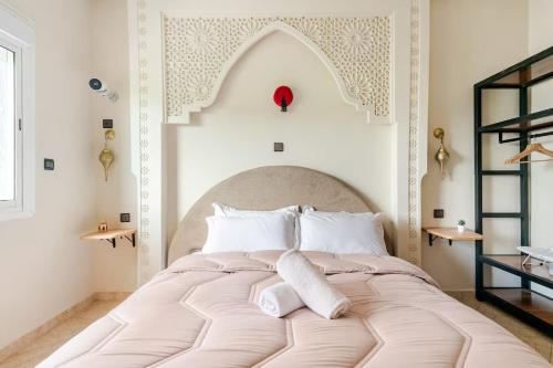 a bedroom with a large bed with white pillows at Eden Appartement avec Piscine Et Salle de Sport in El Jadida