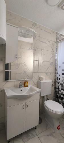 a white bathroom with a toilet and a sink at Apartmani Hena in Sjenica