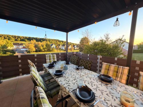a dining table on a patio with a view at Ferienhaus mit Whirlpool, Garten und großer Terrasse ruhig privat in Herbstein
