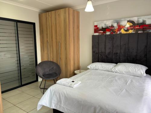 a bedroom with a white bed and a chair at Cozy&Pristine The Blyde in Pretoria