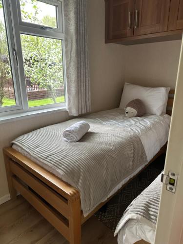 a bedroom with a bed with a teddy bear on it at Tiggywinkle Beck Lodge in Windermere