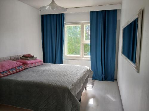 a bedroom with a bed with blue curtains and a window at Kolmio Väinöläntie 6 in Lieksa