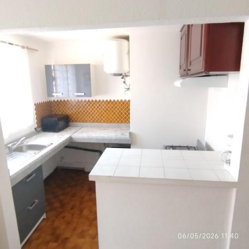 a white kitchen with a sink and a mirror at Tikanel in Schœlcher