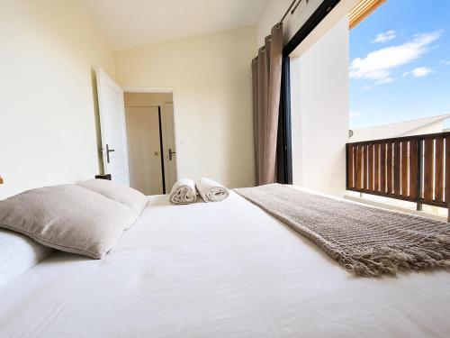 a bedroom with a large white bed with a large window at Villa des trois singes in Saint-Pierre