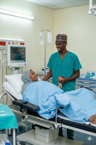 a man standing next to a woman in a hospital bed at Aromat villa in Kano