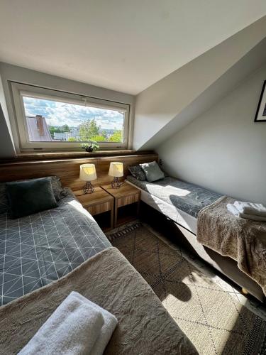 two beds in a room with a window at Pensjonat Krystyna in Rewa