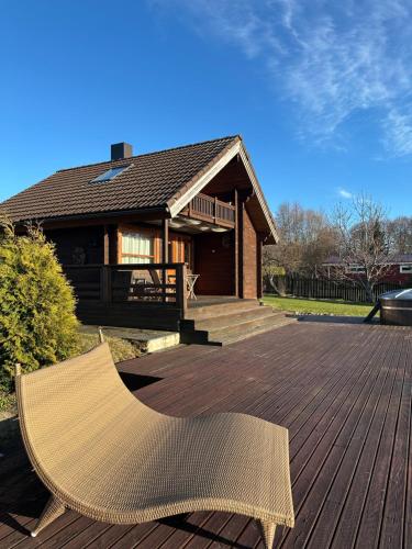 Ein Rattanstuhl steht auf einer Terrasse vor einem Haus. in der Unterkunft Seaside Cabin in Aabla
