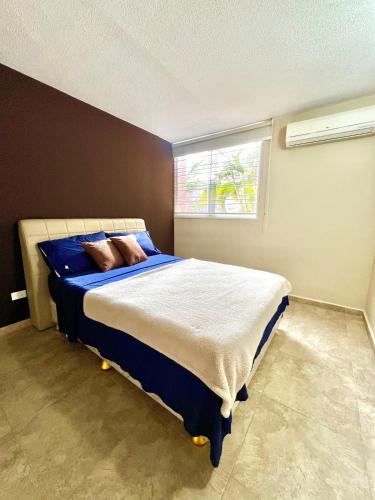 a bedroom with a bed with blue sheets and a window at Coral Suite Excellent location in Porlamar