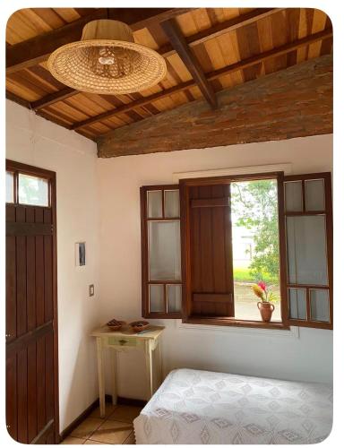 a bedroom with a bed and a window and a table at Casinha das bananeiras in Delfinópolis