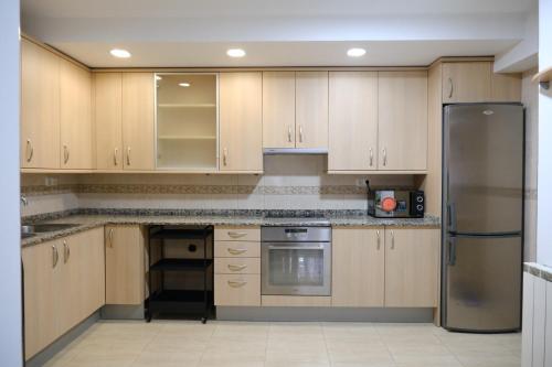 a kitchen with wooden cabinets and a stainless steel refrigerator at Apartament Esmolet in La Pobla de Segur