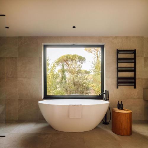 a bath tub in a bathroom with a large window at Sublime Comporta in Comporta