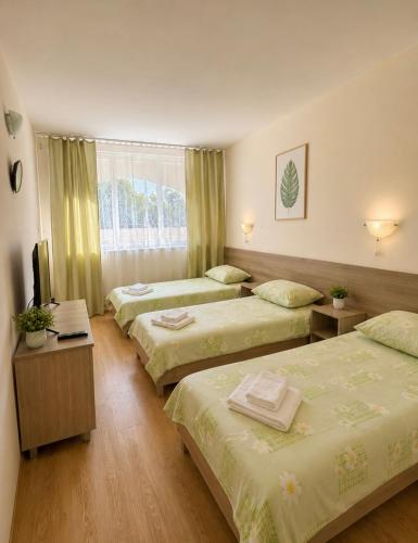 a hotel room with three beds and a television at Hotel Olimpiya in Balchik