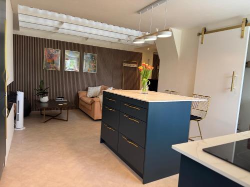 a kitchen with a blue island with a vase of flowers on it at Little Rozel in East Grinstead