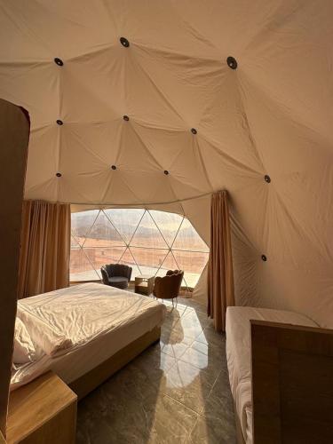 a bedroom with a tent with a bed and a chair at MAJDOLINE Desert Camp in Wadi Rum