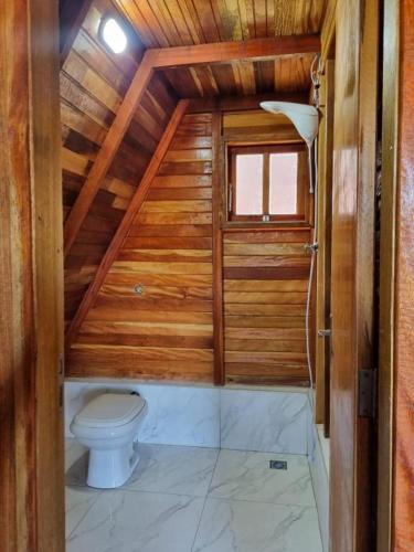 a bathroom with a toilet in a wooden house at Pousada Vista da Mantiqueira - Chalés Sabiá, Beija-Flor e Siriema in Extrema