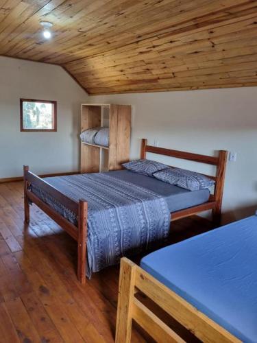 a bedroom with two beds and a wooden ceiling at Pousada Vista da Mantiqueira - Chalés Sabiá, Beija-Flor e Siriema in Extrema