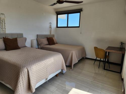 a room with two beds and a table and a window at Apartment in Chixchulub with a spectacular view in Chicxulub