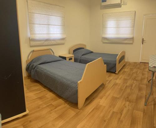 two beds in a room with wooden floors and two windows at دور سياحي in Abha