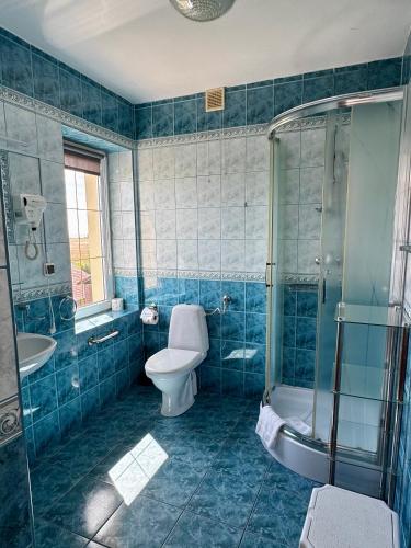 a blue tiled bathroom with a toilet and a shower at Pensjonat Krystyna in Rewa