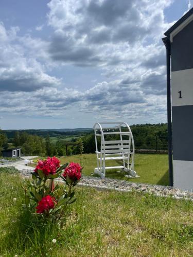 a white bench sitting on top of a field with flowers at Domek Na Wzgórzu Roztocze in Majdan Abramowski
