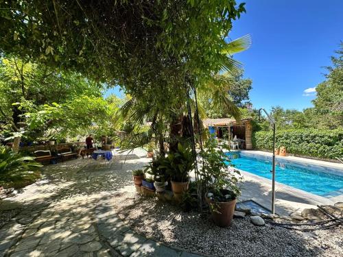 a pool with trees and plants next to a house at Vega Fuente de las Moreras in Burunchel